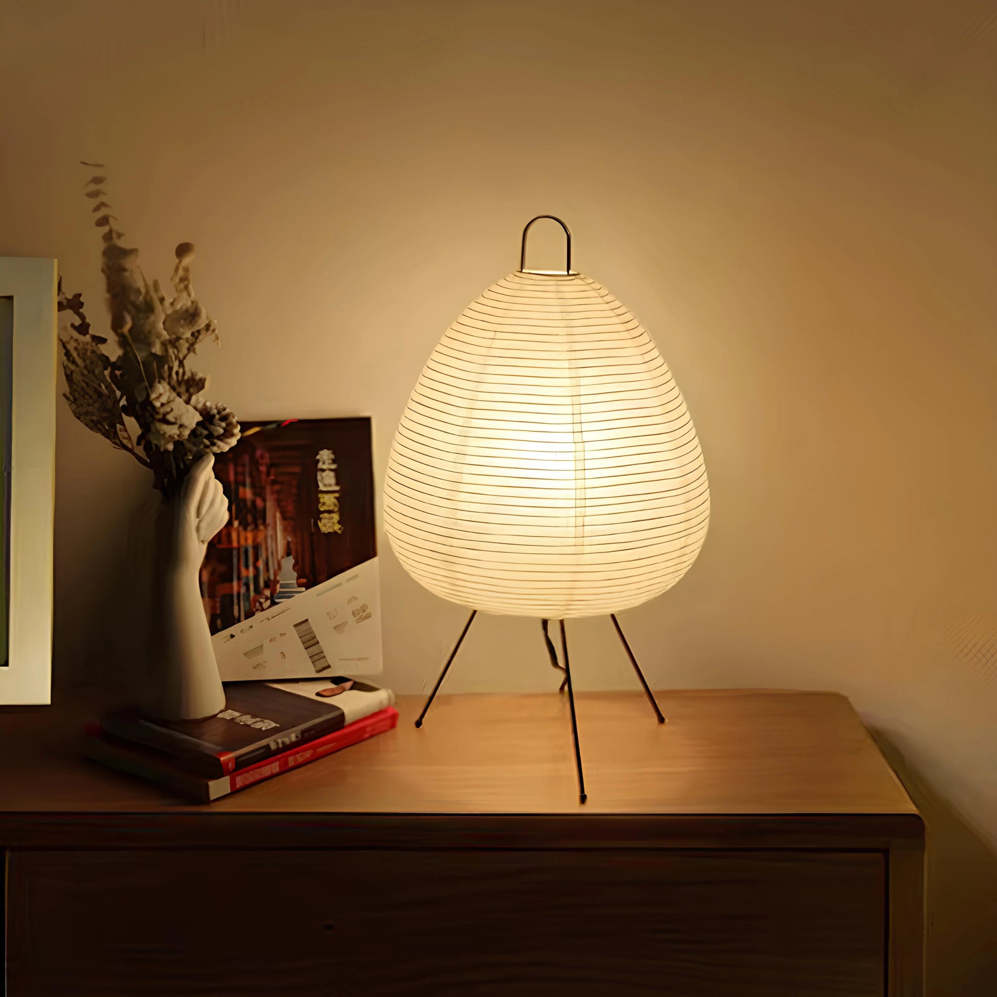 Lummero - lamp on a wooden surface with a warm glow, books, and a vase in the background.