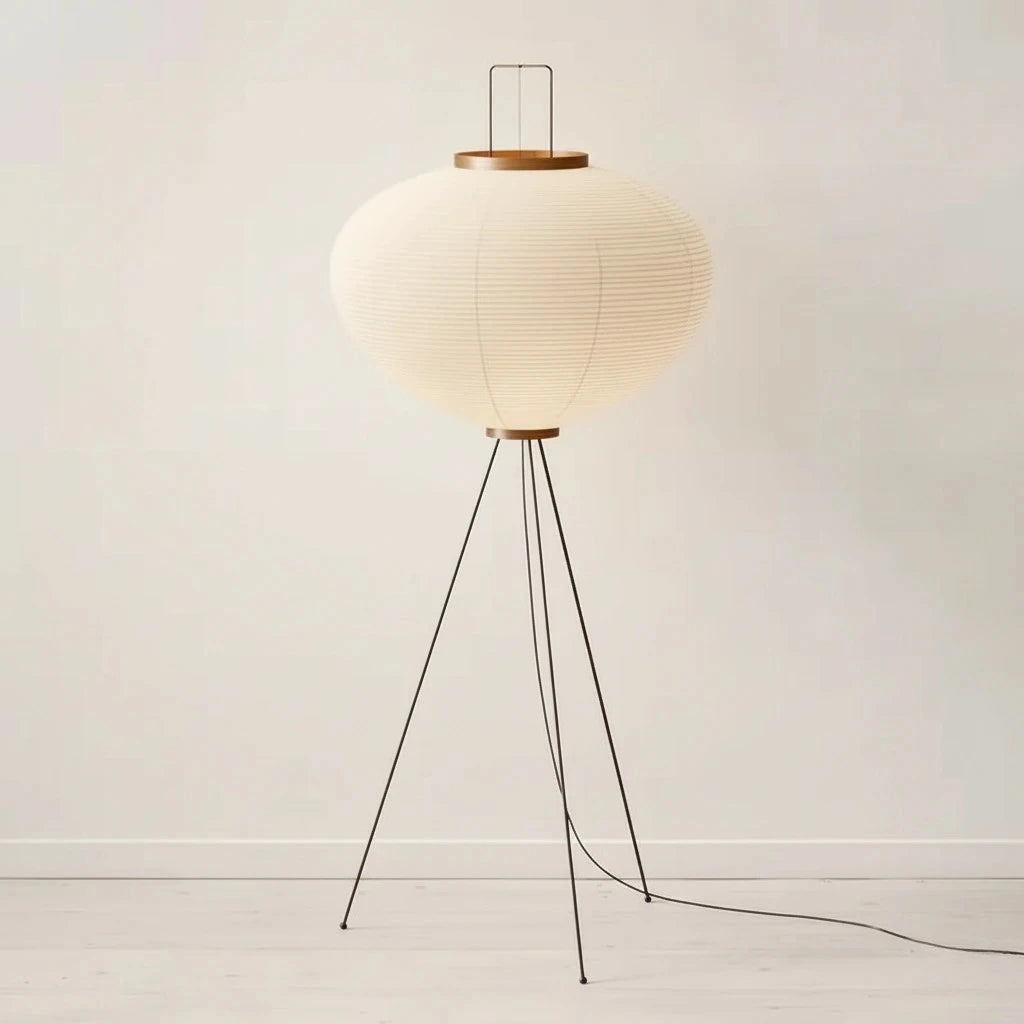 Modern floor lamp with a white shade and black metal legs on a plain background